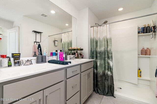 bathroom with tile patterned floors, vanity, and walk in shower