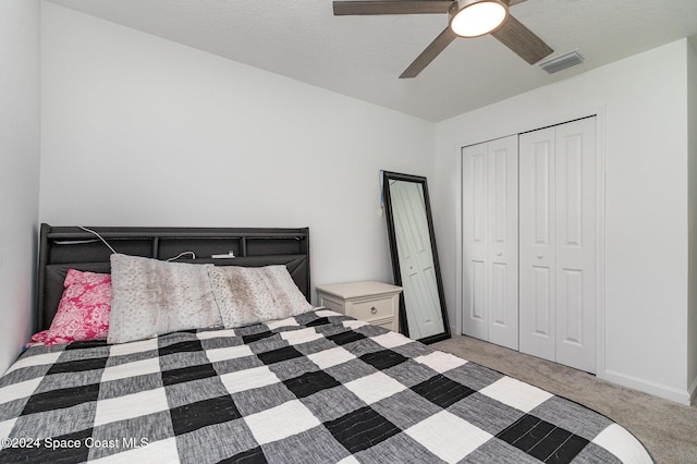 carpeted bedroom with ceiling fan, a textured ceiling, and a closet