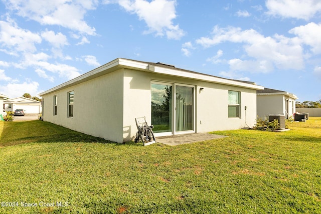 rear view of property featuring a lawn and central air condition unit