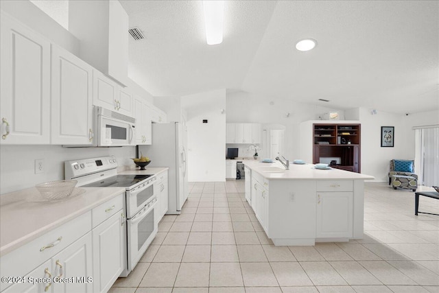 kitchen featuring white cabinetry, vaulted ceiling, white appliances, a kitchen island with sink, and light tile patterned floors