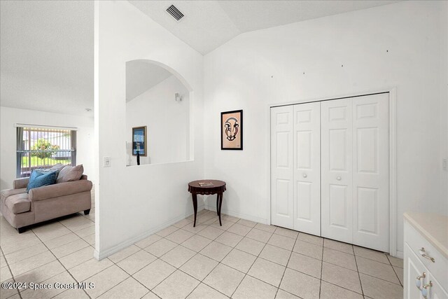 interior space with light tile patterned flooring and vaulted ceiling