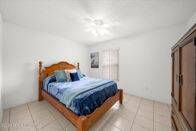 bedroom with ceiling fan, light tile patterned floors, and a textured ceiling