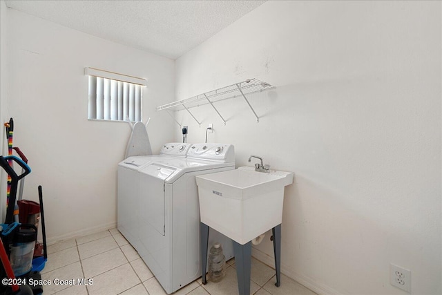 washroom with light tile patterned floors, a textured ceiling, and separate washer and dryer