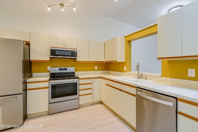 kitchen with light hardwood / wood-style floors, sink, stainless steel appliances, and vaulted ceiling