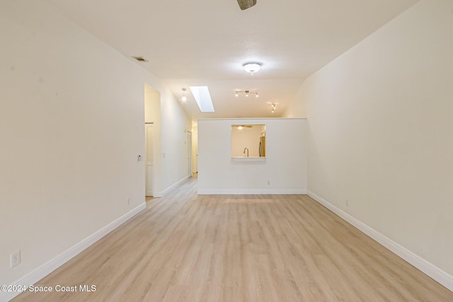 spare room featuring light hardwood / wood-style floors and lofted ceiling with skylight