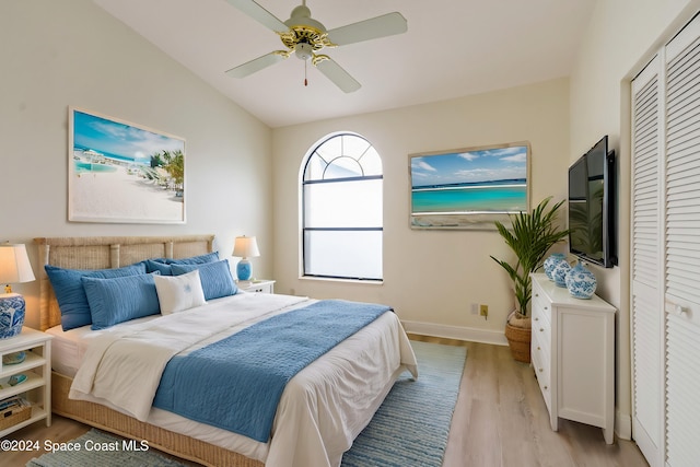 bedroom featuring ceiling fan, light hardwood / wood-style floors, lofted ceiling, and a closet