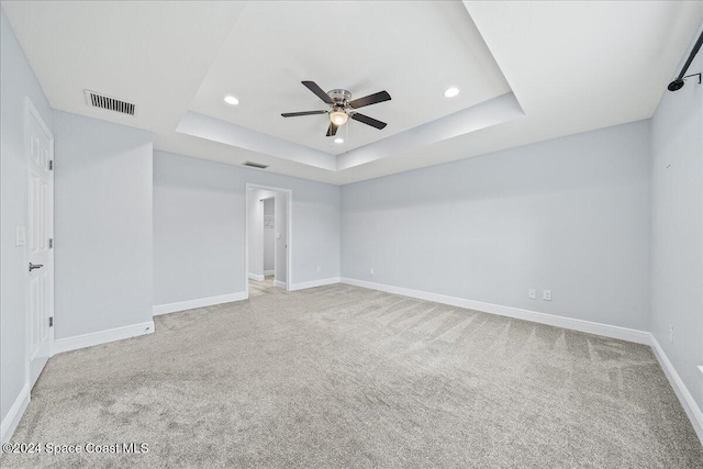 carpeted empty room featuring a raised ceiling and ceiling fan