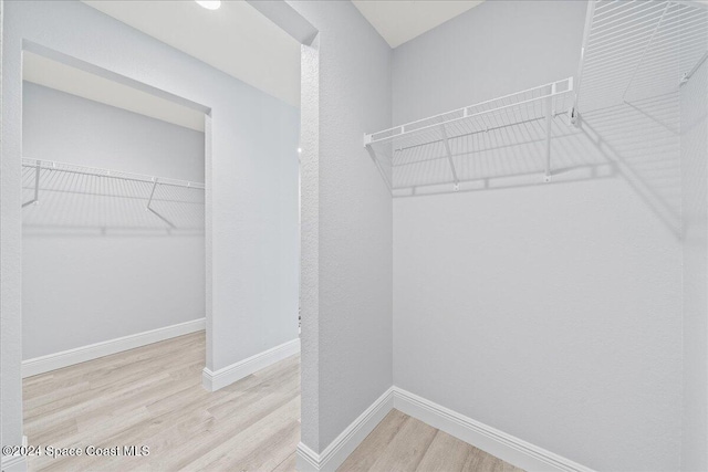 walk in closet with light hardwood / wood-style floors