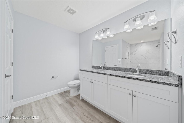 bathroom with tiled shower, toilet, vanity, and hardwood / wood-style flooring