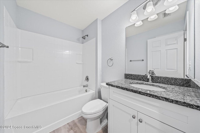 full bathroom with bathing tub / shower combination, toilet, vanity, and hardwood / wood-style flooring