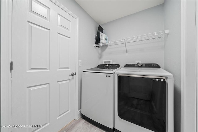 laundry area with washer and clothes dryer and light hardwood / wood-style floors