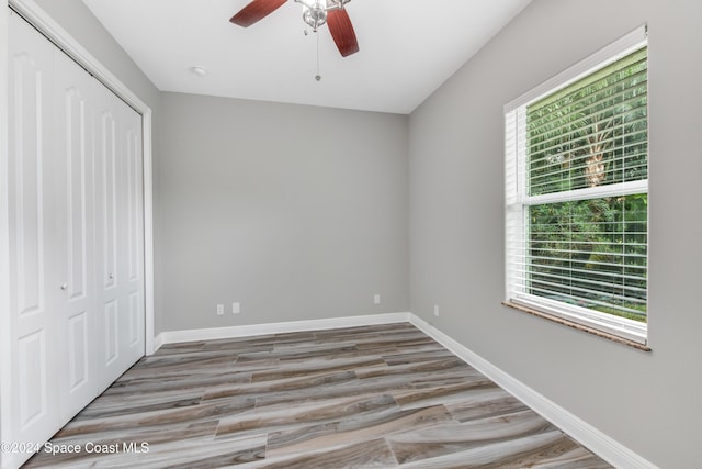 unfurnished bedroom with wood-type flooring, a closet, and ceiling fan