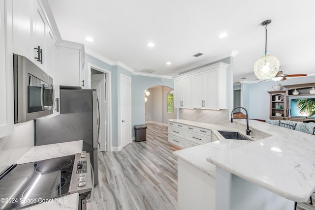 kitchen with kitchen peninsula, crown molding, sink, pendant lighting, and white cabinets