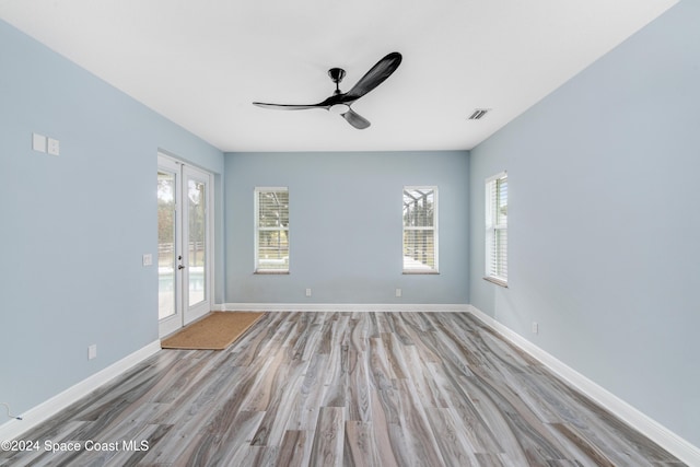 unfurnished room with ceiling fan, light wood-type flooring, a wealth of natural light, and french doors