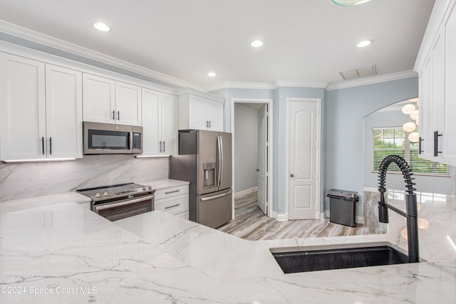 kitchen with white cabinets, sink, light stone countertops, and stainless steel appliances