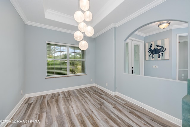 unfurnished room featuring a tray ceiling, ornamental molding, and light wood-type flooring