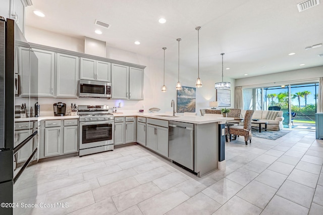 kitchen with appliances with stainless steel finishes, decorative light fixtures, gray cabinets, and sink