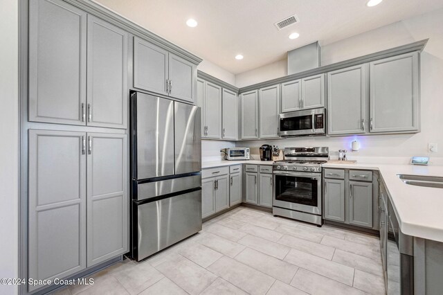 kitchen with gray cabinetry and appliances with stainless steel finishes