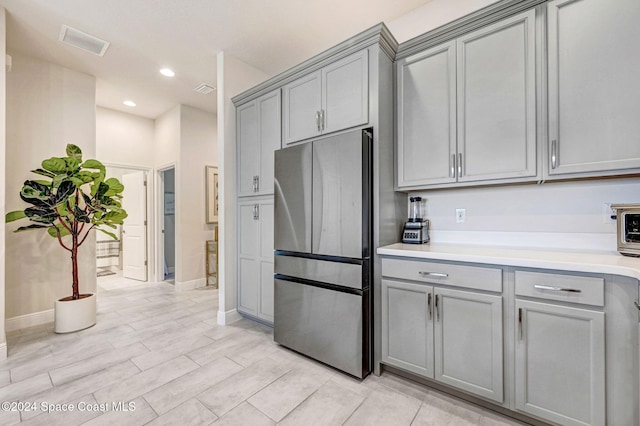 kitchen with gray cabinetry, stainless steel fridge, and light wood-type flooring