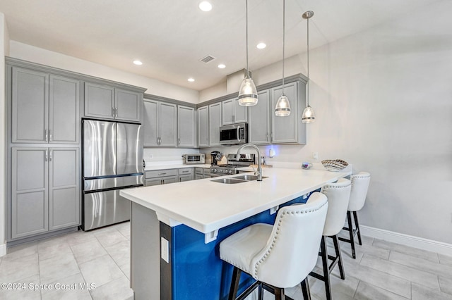 kitchen with gray cabinetry, kitchen peninsula, decorative light fixtures, and appliances with stainless steel finishes