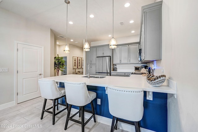 kitchen with sink, a kitchen bar, hanging light fixtures, and appliances with stainless steel finishes