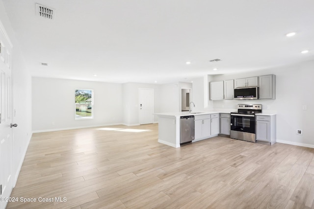 kitchen featuring sink, kitchen peninsula, gray cabinets, appliances with stainless steel finishes, and light wood-type flooring