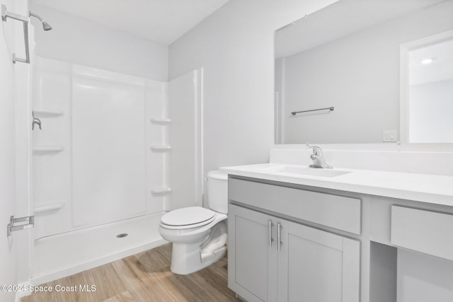 bathroom with a shower, hardwood / wood-style floors, vanity, and toilet