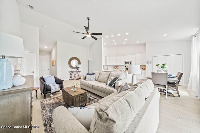 living room featuring high vaulted ceiling, ceiling fan, and light hardwood / wood-style floors