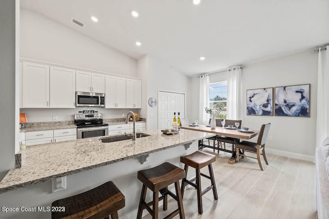 kitchen featuring sink, white cabinets, a breakfast bar, and appliances with stainless steel finishes