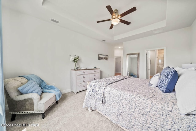 bedroom with ceiling fan, a closet, ensuite bath, a tray ceiling, and light colored carpet