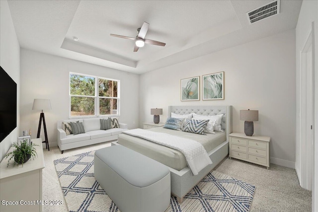 bedroom with ceiling fan, light carpet, and a raised ceiling