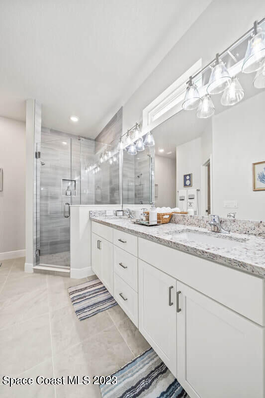 bathroom with a shower with door, tile patterned flooring, and vanity