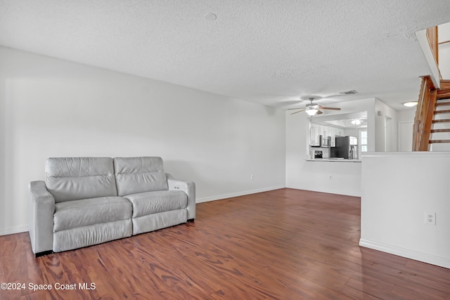 unfurnished living room featuring ceiling fan, dark hardwood / wood-style flooring, and a textured ceiling