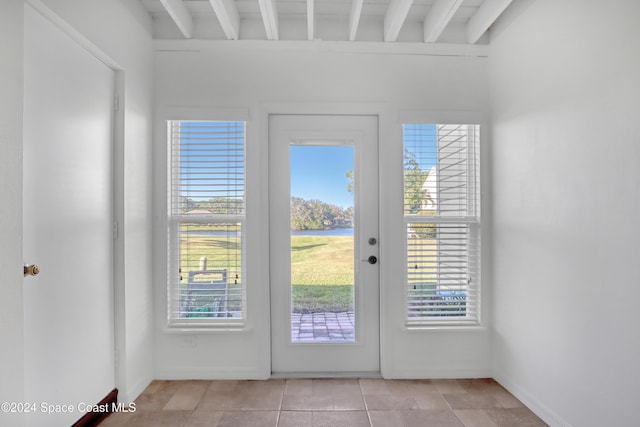 doorway featuring beam ceiling and light tile patterned floors