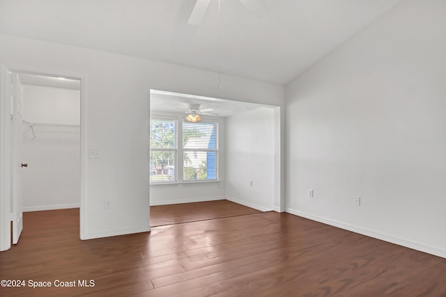 empty room with dark hardwood / wood-style flooring, vaulted ceiling, and ceiling fan