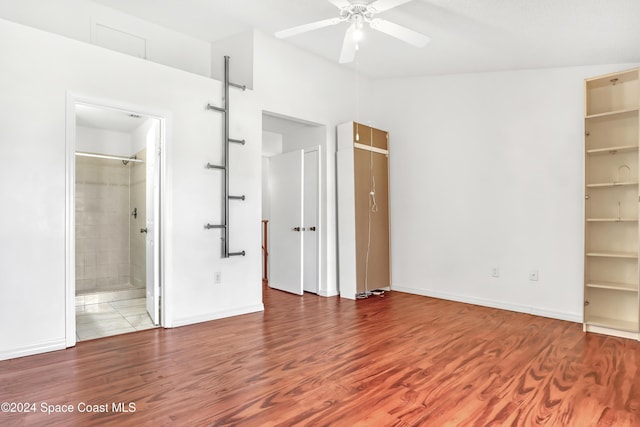 unfurnished bedroom with hardwood / wood-style flooring, ceiling fan, a walk in closet, and connected bathroom