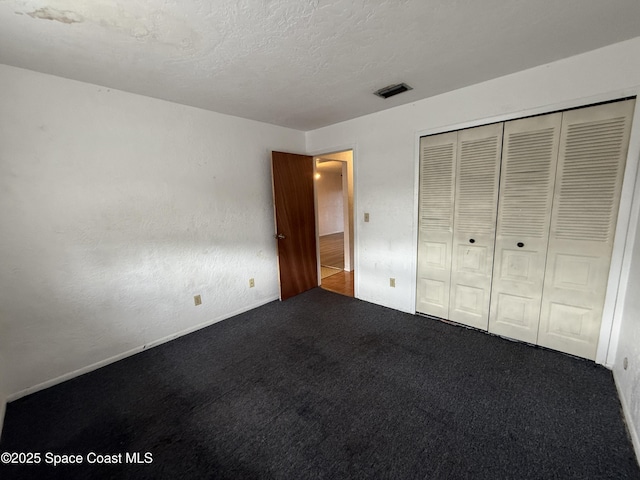 unfurnished bedroom featuring a closet, a textured ceiling, and carpet flooring