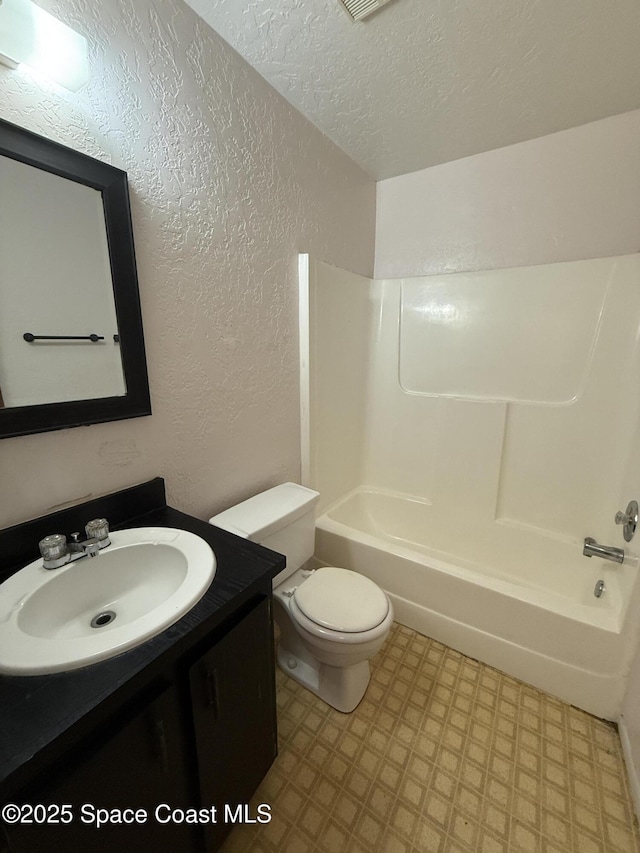 full bathroom featuring vanity, bathtub / shower combination, toilet, and a textured ceiling