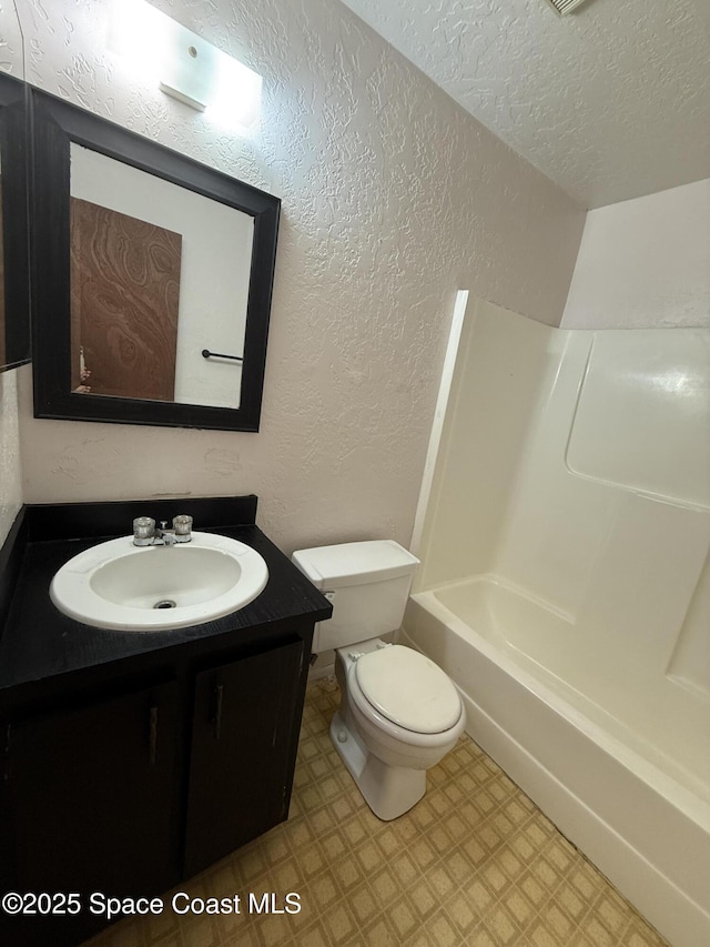 full bathroom featuring vanity, bathtub / shower combination, a textured ceiling, and toilet