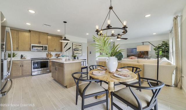 kitchen with appliances with stainless steel finishes, backsplash, pendant lighting, a notable chandelier, and a center island