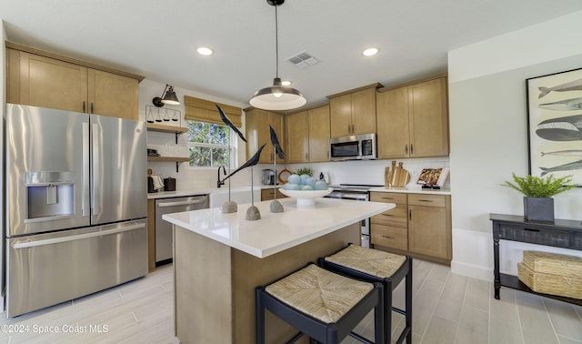 kitchen with light hardwood / wood-style flooring, backsplash, pendant lighting, a kitchen island, and appliances with stainless steel finishes