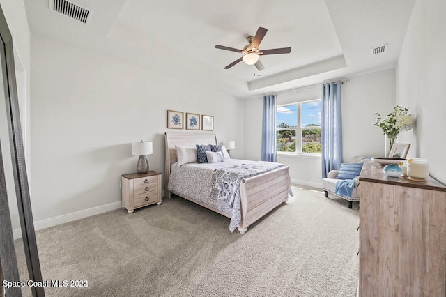 carpeted bedroom featuring ceiling fan and a tray ceiling