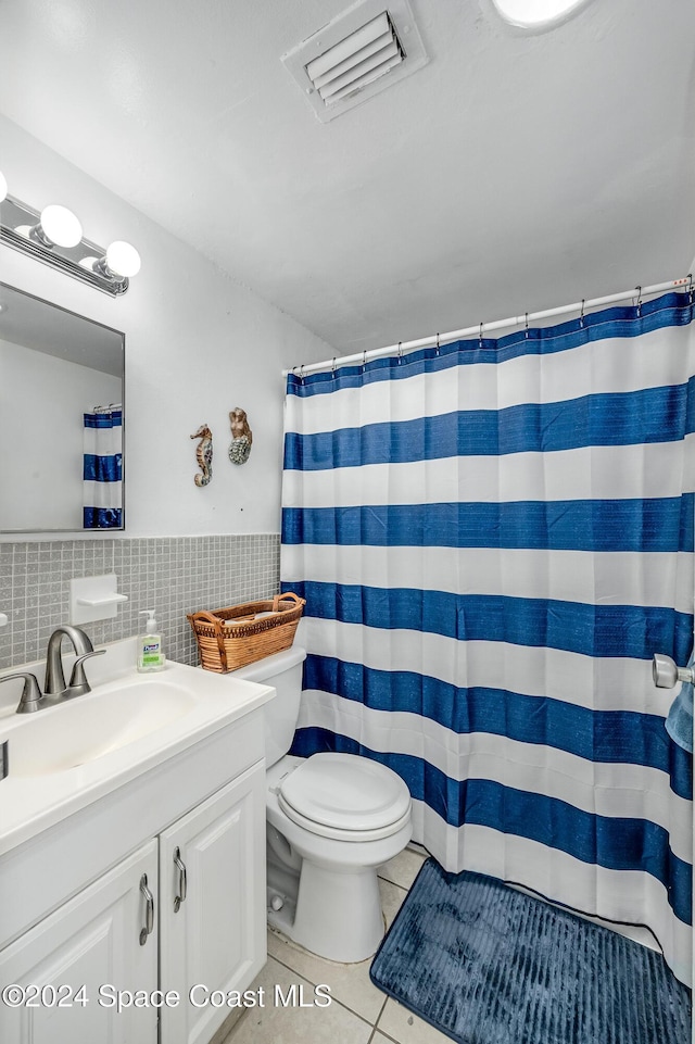 bathroom featuring tile patterned flooring, toilet, decorative backsplash, vanity, and tile walls