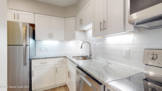 kitchen featuring appliances with stainless steel finishes, tasteful backsplash, white cabinetry, and sink