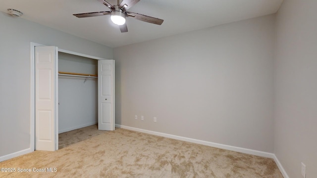 unfurnished bedroom featuring ceiling fan, a closet, and light carpet