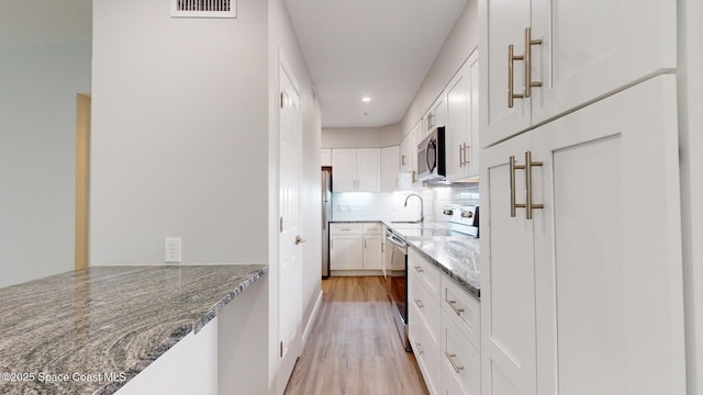 kitchen featuring decorative backsplash, appliances with stainless steel finishes, light hardwood / wood-style flooring, stone counters, and white cabinetry