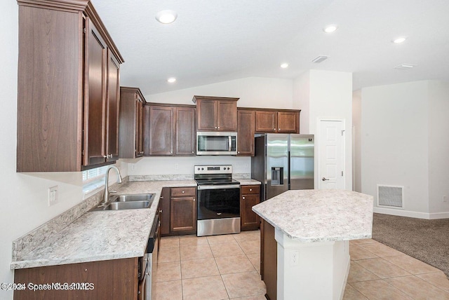 kitchen featuring light tile patterned floors, vaulted ceiling, stainless steel appliances, and a kitchen island