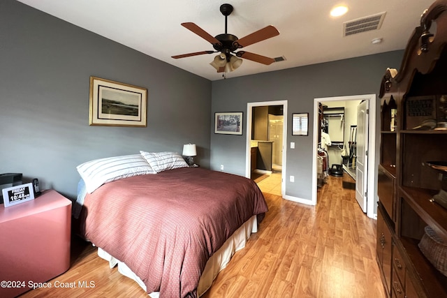 bedroom with ensuite bath, ceiling fan, light wood-type flooring, a spacious closet, and a closet