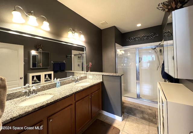 bathroom with a shower with door, vanity, and tile patterned flooring