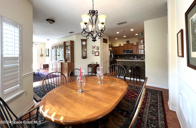 dining area featuring wood-type flooring and an inviting chandelier